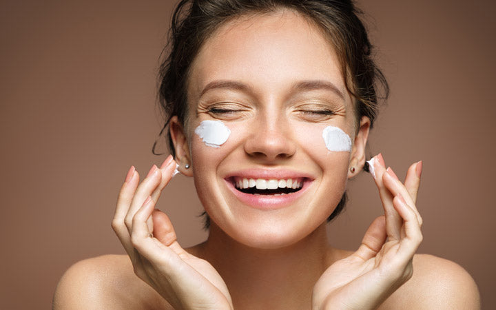  Vrouw brengt moisturizer aan met gelukkig gezicht