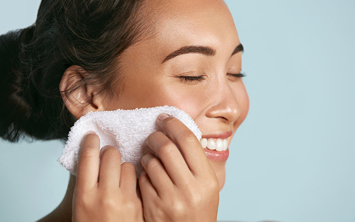 vrouw die gezichtshuid met handdoek reinigt na het wassen van het gezicht