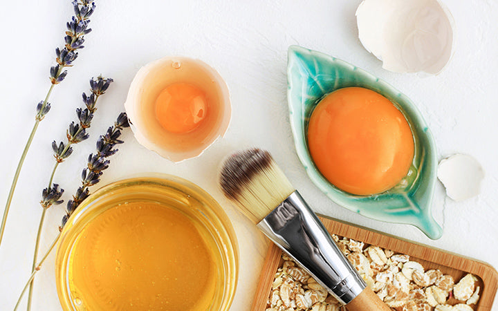 heldere eierdooiers, havervlokken, honing, lavendel met cosmetische borstel close-up, natuurlijke holistische ingrediënten voor zelfgemaakte schoonheidsverzorging