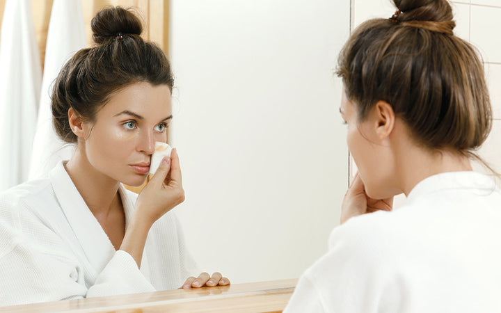 Vrouw kijkt in de spiegel en verwijdert make-up