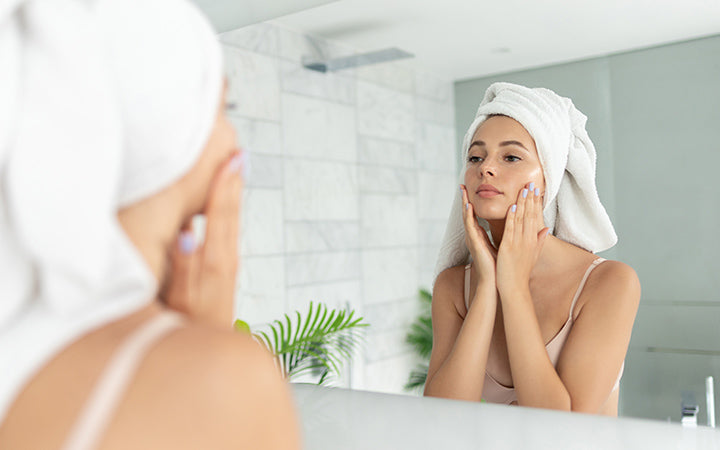Vrouw die huid gezichtscrème vochtinbrengende lotion gebruikt na het nemen van bad