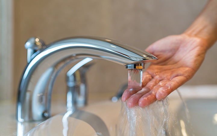 Vrouw die de temperatuur controleert en stromend water met de hand aanraakt