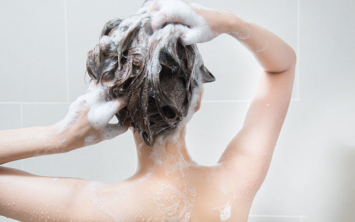 vrouw in douche wassend haar met shampoo