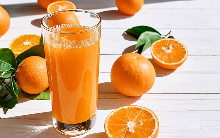 Rijpe bio sinaasappels en een glas vers geperst sinaasappelsap