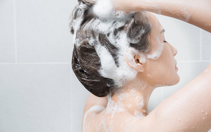 Vrouw die haar haar wast met shampoo